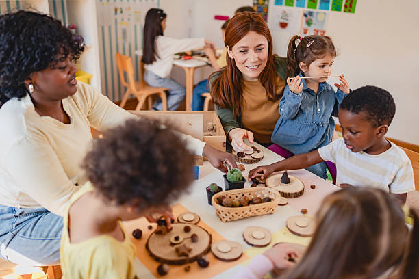 istock Diverse group of preschool children engage in a nature-based learning activity with two teachers, using wood and natural objects to explore creativity and tactile skills in the classroom. 2209613008