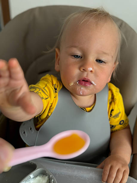 istock Baby eating his food with hands and spoon 2209613518