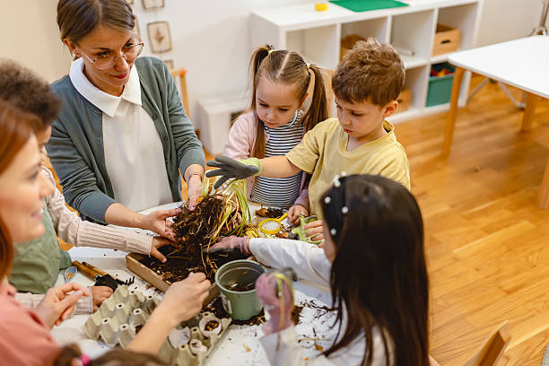 istock Teacher and curious children explore soil and plants in a classroom science activity, encouraging hands-on learning and environmental awareness in a diverse group of students. 2209616106