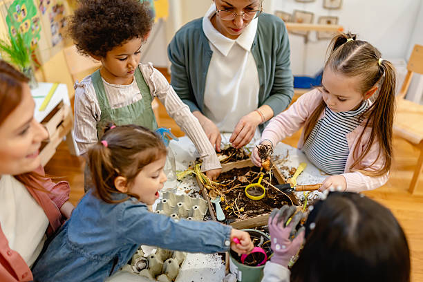 Children explore plant bulbs and soil during a hands-on gardening activity, promoting environmental education and sensory learning in a diverse classroom setting.