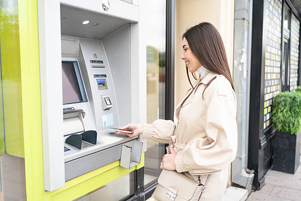 istock Young woman withdrawing money at an ATM 2209616268