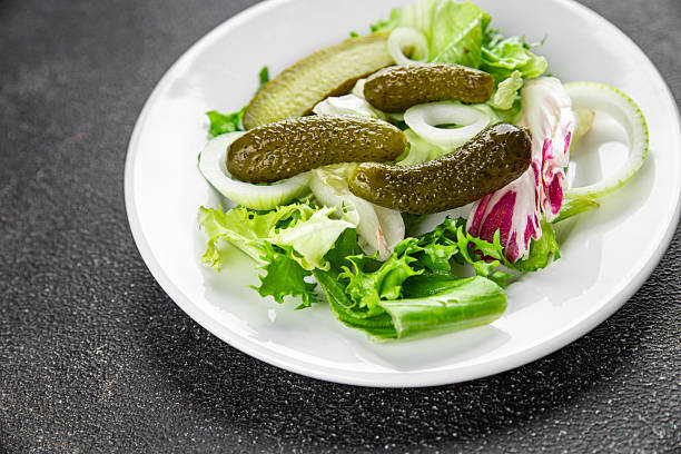 Pickle salad gherkins pickled cucumbers mixed green leaf lettuce appetizer vegetables dish organic fresh tasty gourmet food background on the table food top view copy space vegetarian vegan food