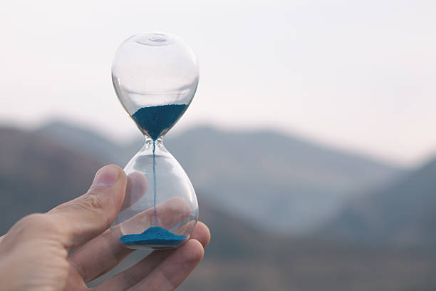 istock hand holding glass hourglass on blurred background 2209618854