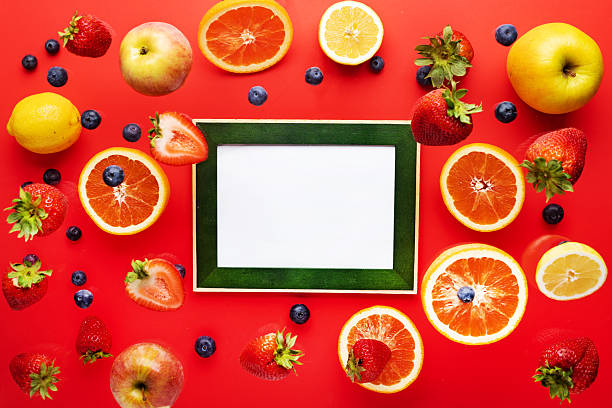 levitating blueberries, strawberries, apples and oranges on a red background. Photo frame for text. View from above.
