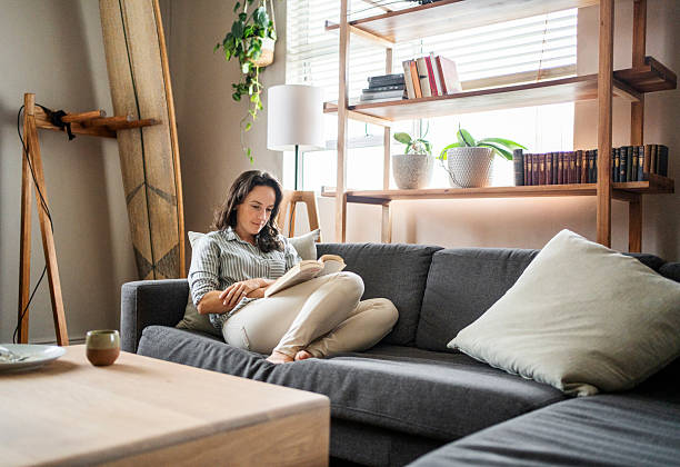 istock Woman relaxing on the sofa reading a book in her apartment 2209625154
