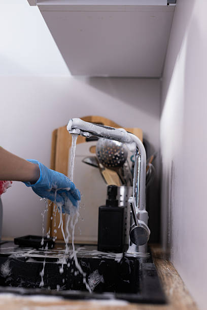 istock A close-up view of a hand using a faucet with soapy water, emphasizing cleanliness while preparing to do the dishes in a cozy kitchen setting with utensils in the background. 2209626516