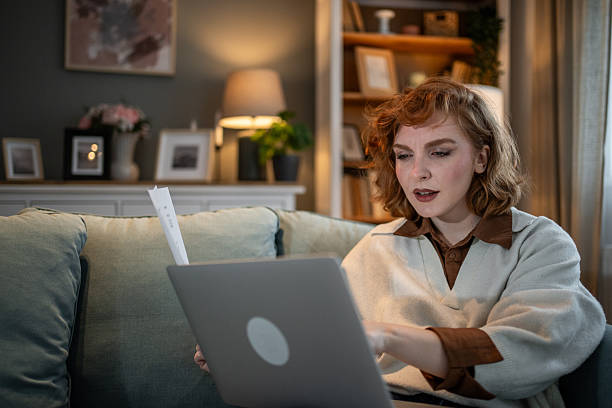 istock Focused young woman working from home on laptop with documents 2209628657
