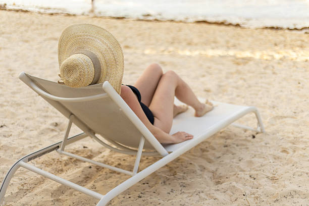 istock Relaxing in the sun on a beach lounge chair while wearing a large sun hat 2209631644