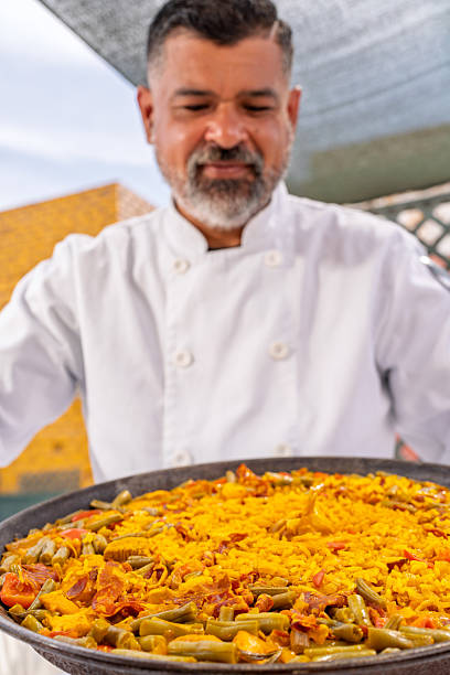 Chef presenting a vibrant paella cooked on a rooftop, ready for family enjoyment during a delightful outdoor meal