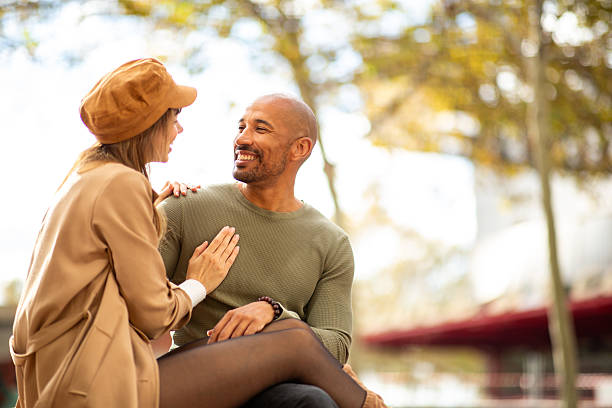 istock relaxed couple sitting in park together looking at each other 2209636444