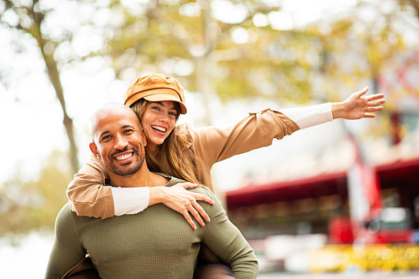 istock cheerful young woman piggyback ride on smiling man 2209636475