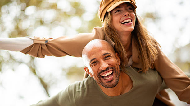 istock happy couple sharing a fun piggyback ride outdoors with arms outstretched 2209636483