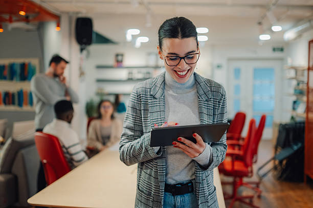 istock Young businesswoman using digital tablet in modern office with colleagues in background 2209636571