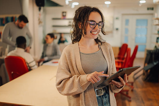 istock Young woman using digital tablet in coworking space with colleagues 2209636589