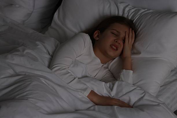 istock Little girl suffering from headache in bed at night 2209638781