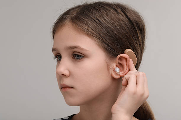 istock Little girl with hearing aid on grey background 2209638849