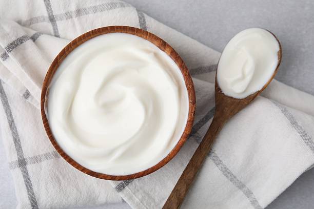 istock Delicious natural yogurt in bowl and spoon on light grey table, top view 2209639669