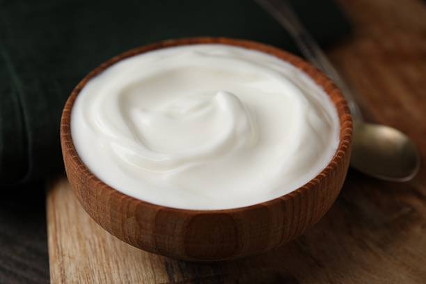 istock Delicious natural yogurt in bowl and spoon on table, closeup 2209639673