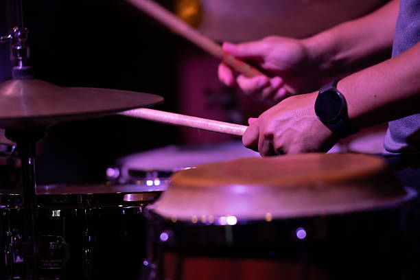 istock Close-up of a drummer's hands playing percussion instruments under stage lighting. 2209640870