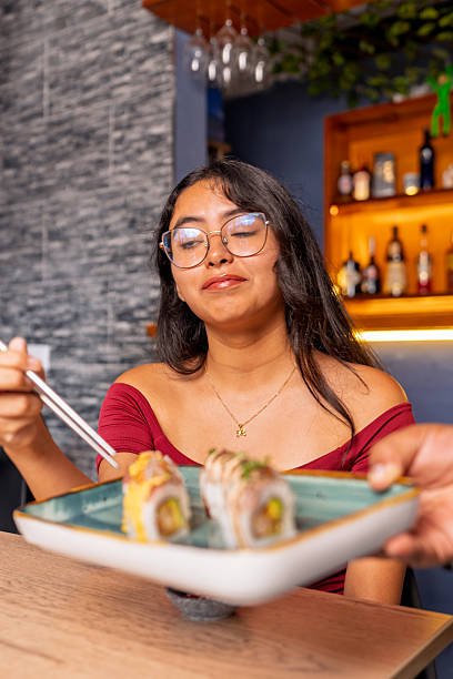 istock Young woman enjoying sushi in a restaurant 2209650188