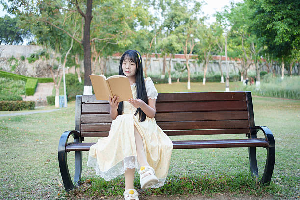 Young man sitting on a park bench and reading a book
