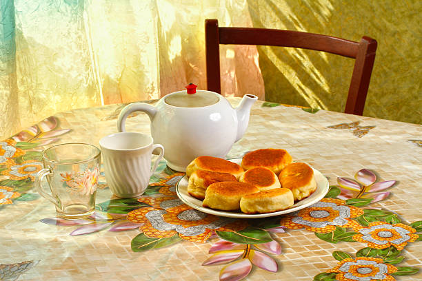Pies, teapot and cups on the table. Plate with fresh homemade pies.