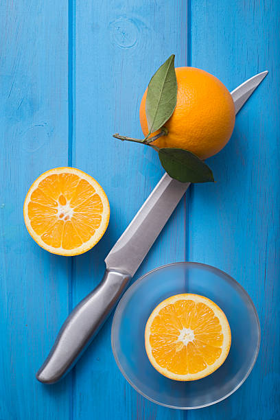 someone cuts oranges with a thin knife or cutter on the table to make juice