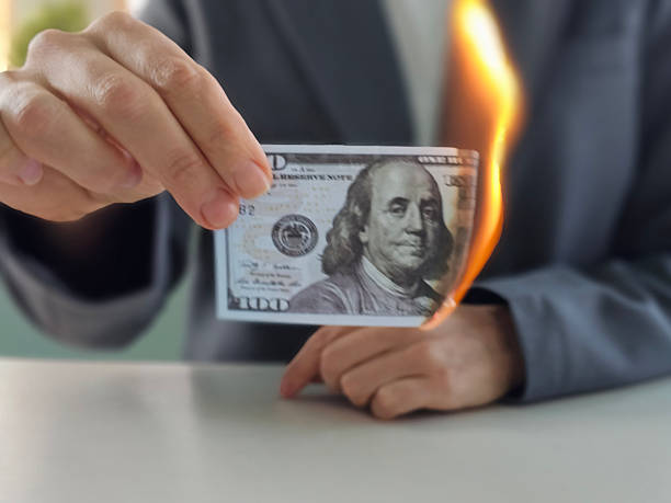 istock Holding a burning hundred dollar bill during a financial demonstration 2209667947