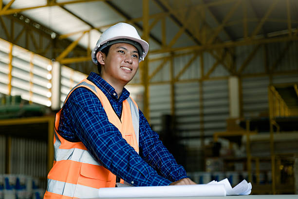 istock Engineer wearing reflective safety jacket discussing over blueprint in industry. 2209669333