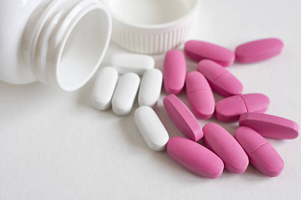 istock Pink and white pills on a white background. Focus on foreground, soft bokeh. 2209672009