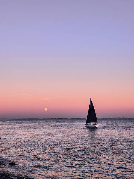 Close-up shot of a sailboat gliding silently across the Atlantic Ocean as the full moon rises into a pastel-toned sky. The hues of pink, purple, and twilight blue blend seamlessly, creating a dreamlike gradient .Concept:\nLisbon seascape, Atlantic moonrise, twilight sailing, pastel sky, peaceful ocean moment, coastal Portugal vibes