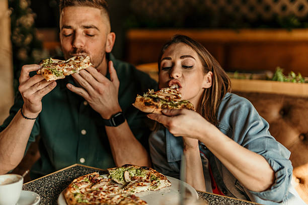 istock Young Couple Enjoying Delicious Pizza at Restaurant 2209673965