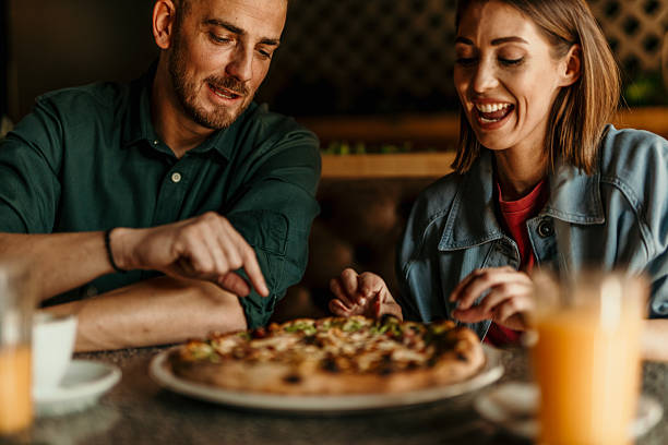 istock Young couple enjoying pizza together at a restaurant 2209674009