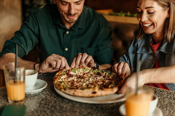 istock Couple sharing pizza at restaurant table, enjoying meal together 2209674010