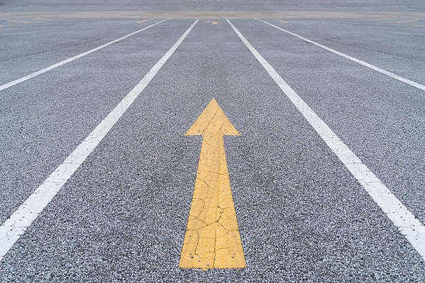istock Disruptive ideas in business. Bold yellow arrow challenging the status quo on asphalt road. 2209681049