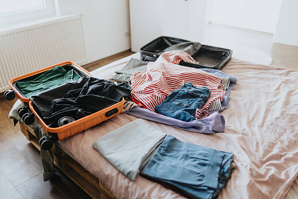 istock Suitcase and clothes on bed in bedroom without people 2209683552