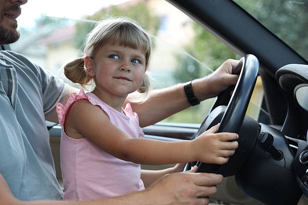 istock Man with his daughter holding steering wheel inside car, closeup 2209685348