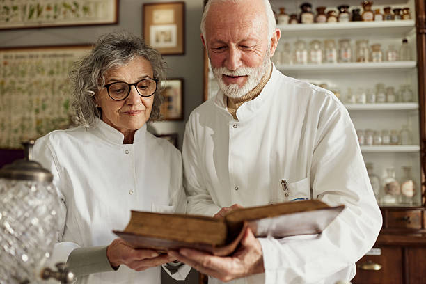 Mature scientists cooperating while reading old medical book in a laboratory.