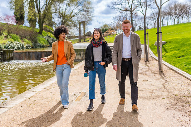 istock Three young adults walking and talking in a sunny park 2209687641