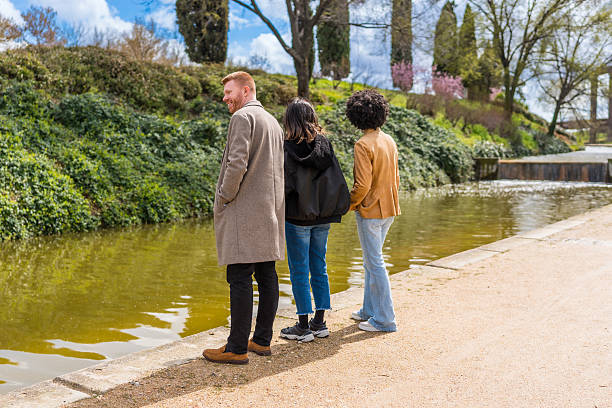 istock Three young adults admiring a pond in a park 2209687667