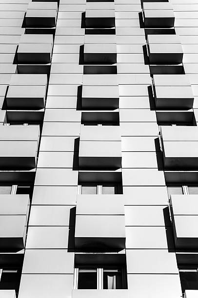 Modern apartment building facade with repeating balconies and high contrast black and white shadow design for urban architecture themes