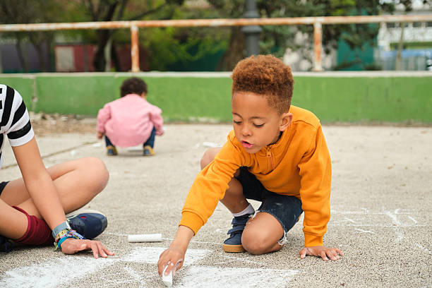 Group of children drawing with chalks on the ground in a playground
