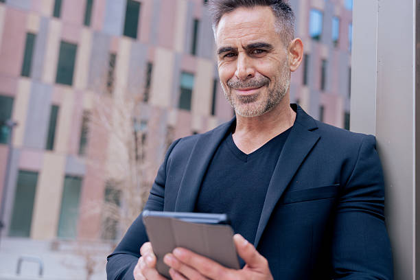 istock Smiling businessman using tablet outdoors in city, confident and modern look 2209693349