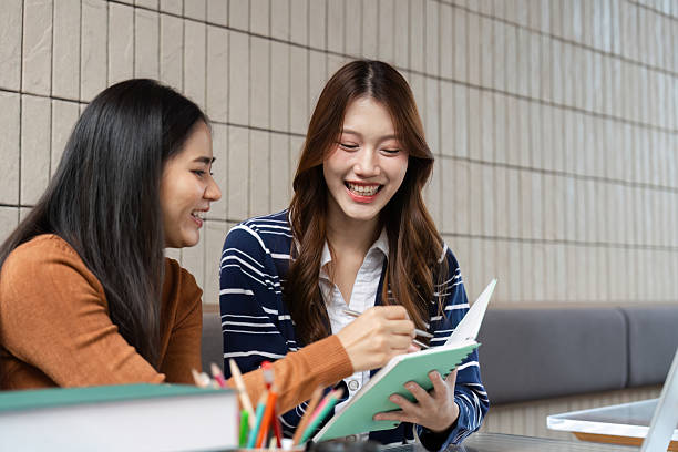 istock Learning and Engagement. Two students happily collaborating on a project, smiling and writing notes. 2209693432