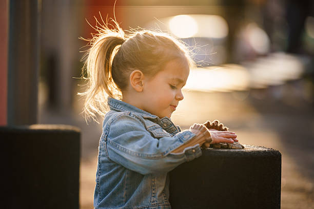 Side view of cute little girl playing whit pebble at the playground
