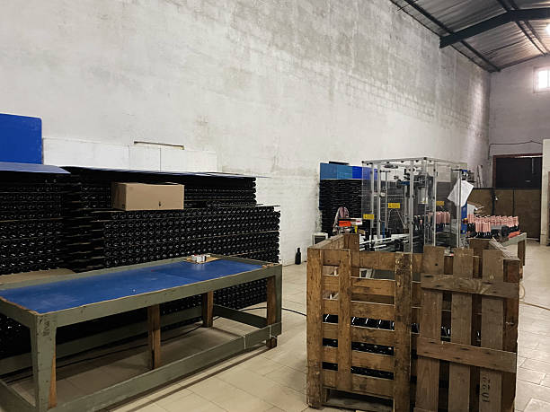 A spacious industrial area with bottling equipment, storage, and wooden pallets.