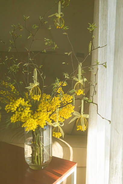 istock Sunny bouquet with yellow mimosa and Easter wire eggs decorations in a vase, captured in soft focus. 2209698754