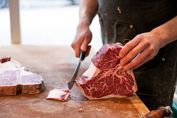 istock Butcher slices raw beef steaks by hand 2209698927