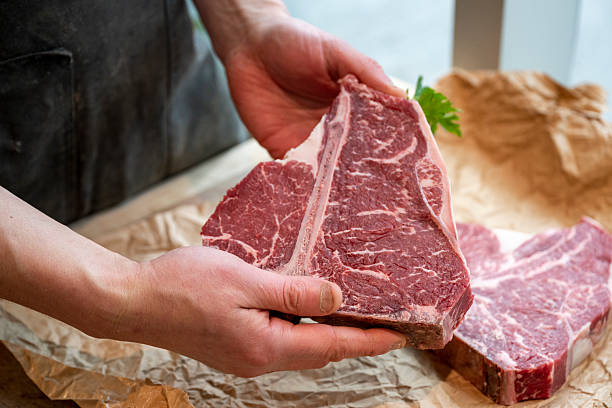 istock Butcher holds raw beef steak in shop 2209699709