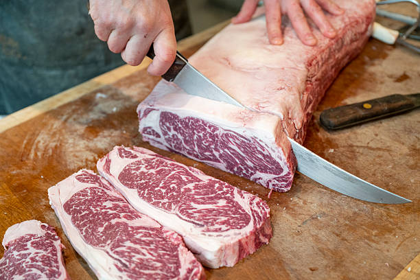 istock Butcher slices raw beef steaks by hand 2209700955